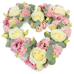 A serene heart-shaped wreath of pastel flowers is displayed against a crisp white backdrop, giving the impression that the blooms are gently floating in space. The heart is completely filled with flowers, creating a plush, almost pillow-like surface that feels visually soft and deeply comforting. Creamy ivory and pale yellow roses act as focal points throughout the design, their full, spiralled centres and smooth petals exuding quiet elegance. Around these, clusters of pale pink carnations with ruffled, intricate edges bring a sense of warmth and familiarity, like a gentle touch on the shoulder during a difficult farewell. Deeper shades of pink and mauve lisianthus are woven in, their more open, trumpet-shaped blossoms adding both movement and emotional depth, a subtle echo of twilight over the green spaces of Hanwell. Silvery-green eucalyptus leaves thread through the arrangement, their rounded forms and matte finish creating a cool, soothing contrast to the softness of the petals and helping define the heart's curved outline. Delicate yellow-green buds peek shyly between flowers, hinting at life continuing even as we pause to remember. The colour palette-creams, blush pinks, deeper rose tones, and muted greens-blends into a harmonious whole that feels peaceful rather than somber. This floral heart could easily be imagined placed beside a casket, at a crematorium, or on a memorial table for a service held near Brent Lodge Park, speaking silently of love, remembrance, and heartfelt condolence. Every element suggests the attentive hands of a local florist who understands how flowers can convey what grieving families in Hanwell sometimes struggle to say aloud.